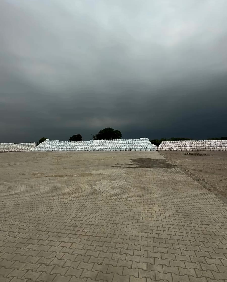 Long rows of wrapped Sardar Silage bales across the Bhadson yard under a dark monsoon sky