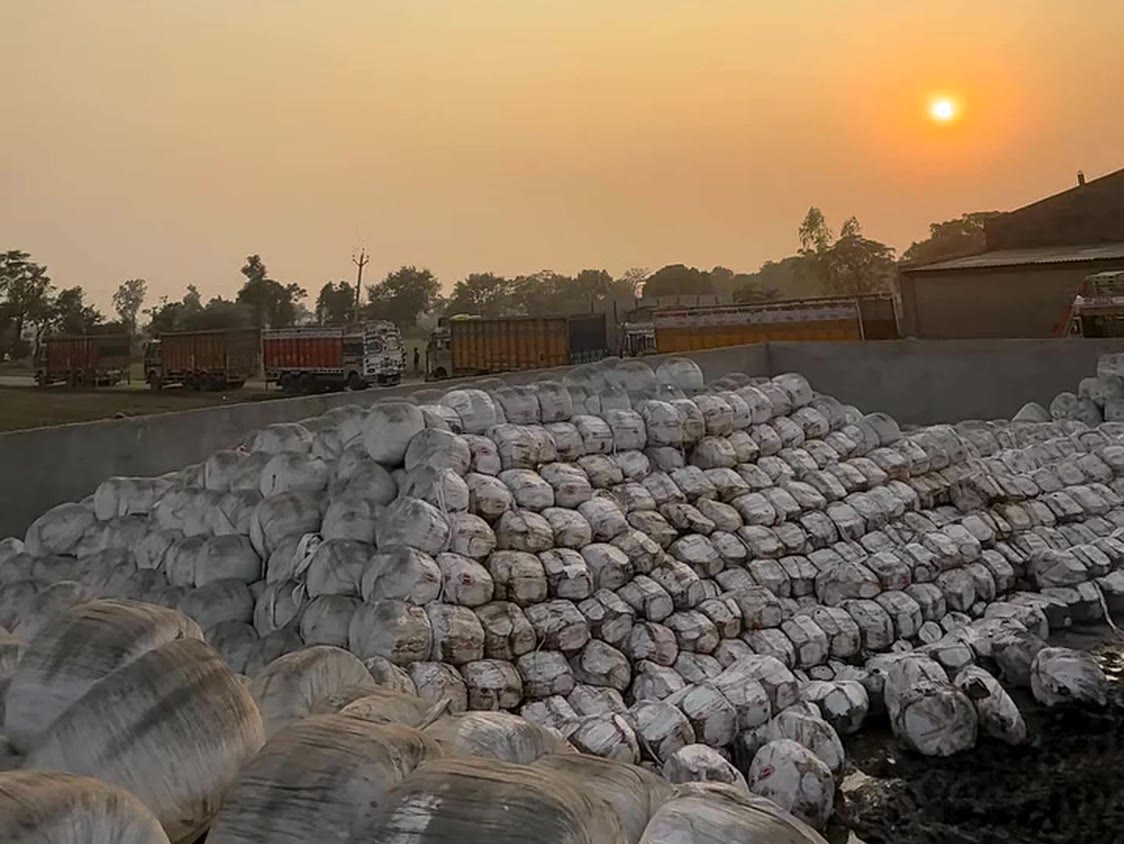 Bales at the yard with trucks waiting at sunset