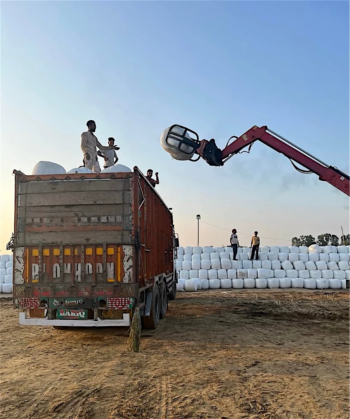 Telehandler loading bales onto a truck in the yard